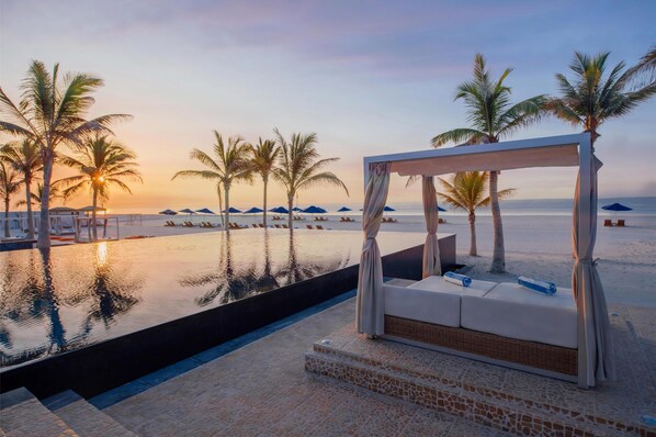 A poolside lounge area with a white canopy, lounge chairs, and a view of the beach and ocean. - Al Baleed Resort Salalah by Anantara (Salalah)