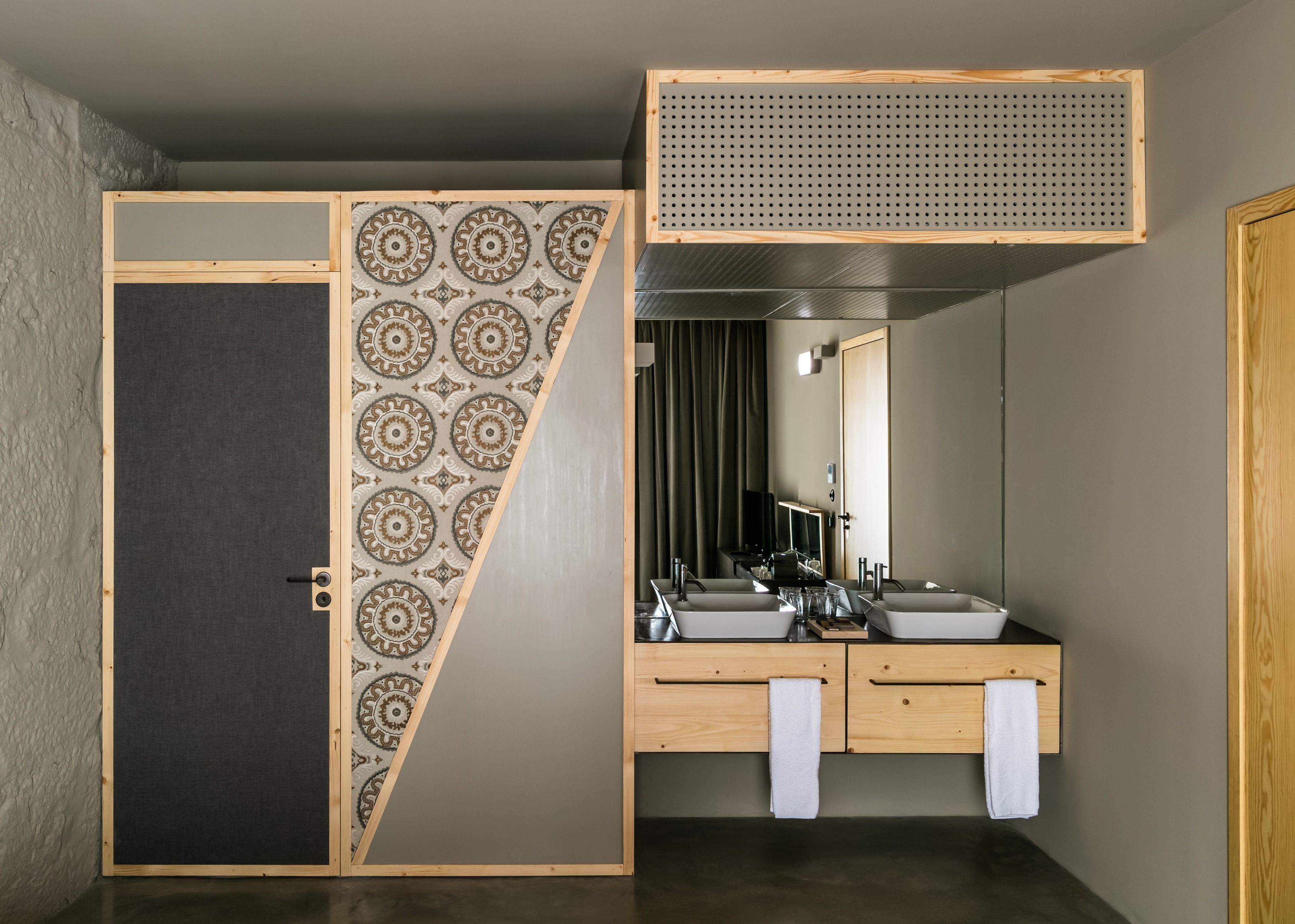 Een badkamer met een houten wastafelmeubel, twee wastafels, een spiegel en een handdoekhouder.