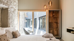 A bedroom with a large bed, a wooden wardrobe, and a view of the outside. - Armazém Luxury Housing (Porto)
