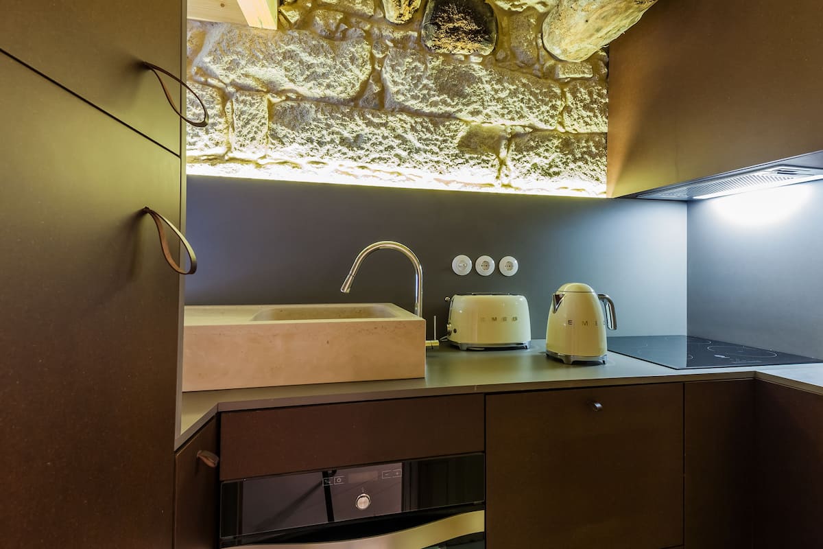 A modern kitchen with a stone backsplash, a built-in sink, a toaster, and a kettle on the countertop.