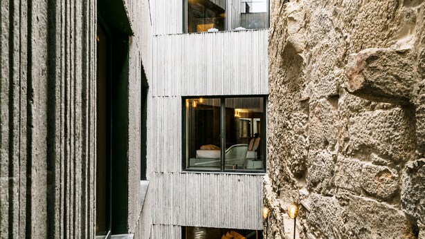 A modern building with a stone facade and a narrow interior corridor. - Armazém Luxury Housing (Porto)