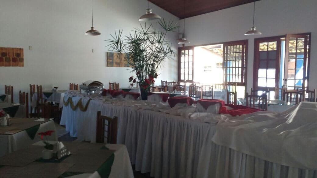 A dining area with tables covered in white tablecloths, wooden chairs, and hanging pendant lights.