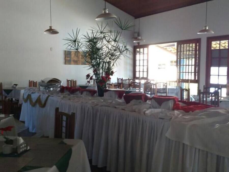 A dining area with tables covered in white tablecloths, wooden chairs, and hanging pendant lights.
