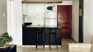 A modern kitchen with a refrigerator, microwave, and bar stools. - Rio Habitat Almirante (Rio de Janeiro)