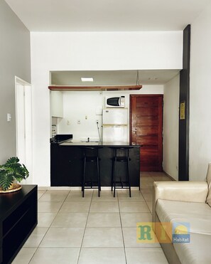 A modern kitchen with a refrigerator, microwave, and bar stools. - Rio Habitat Almirante (Rio de Janeiro)
