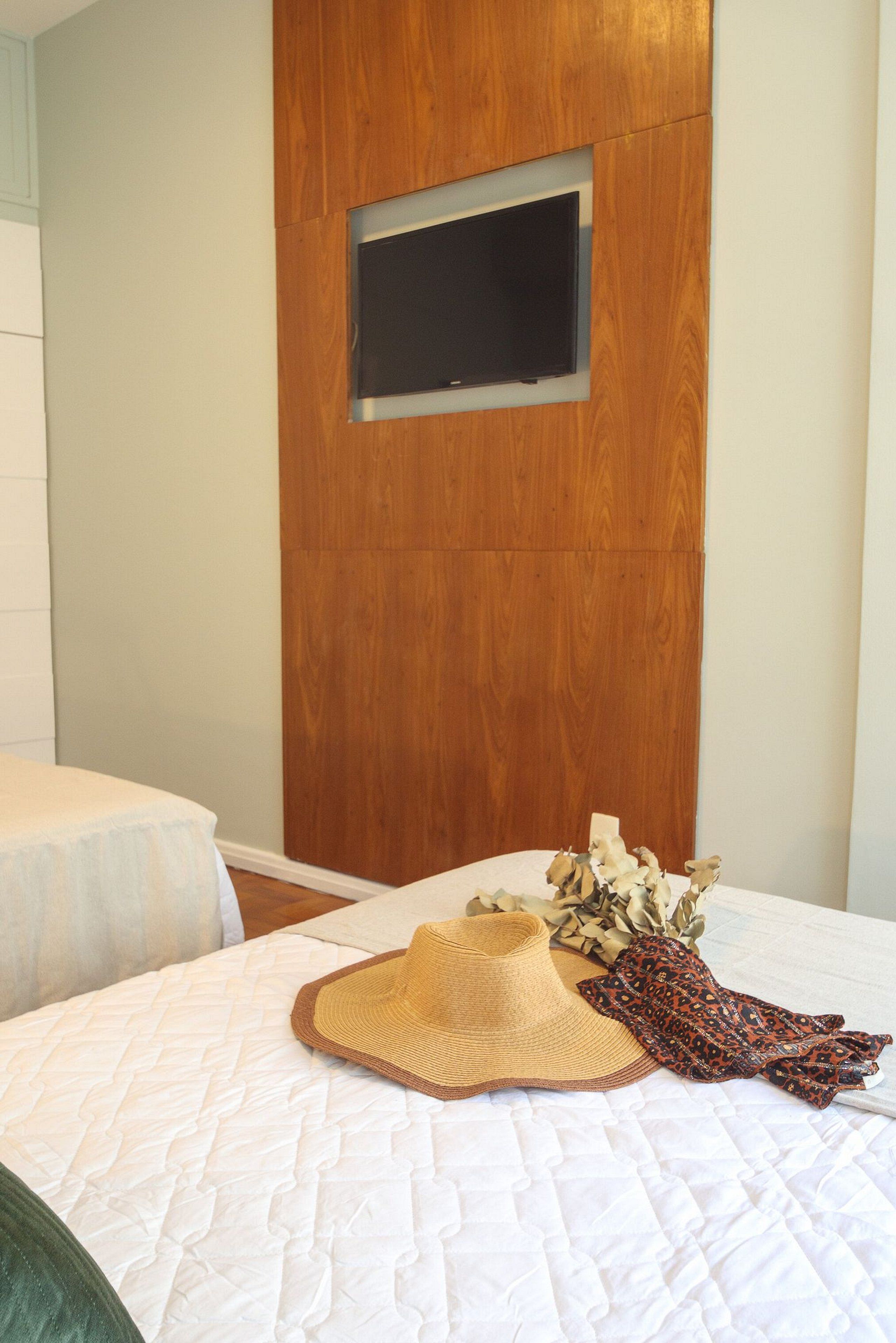 A bedroom with a bed, a wooden panel wall, and a mounted television.