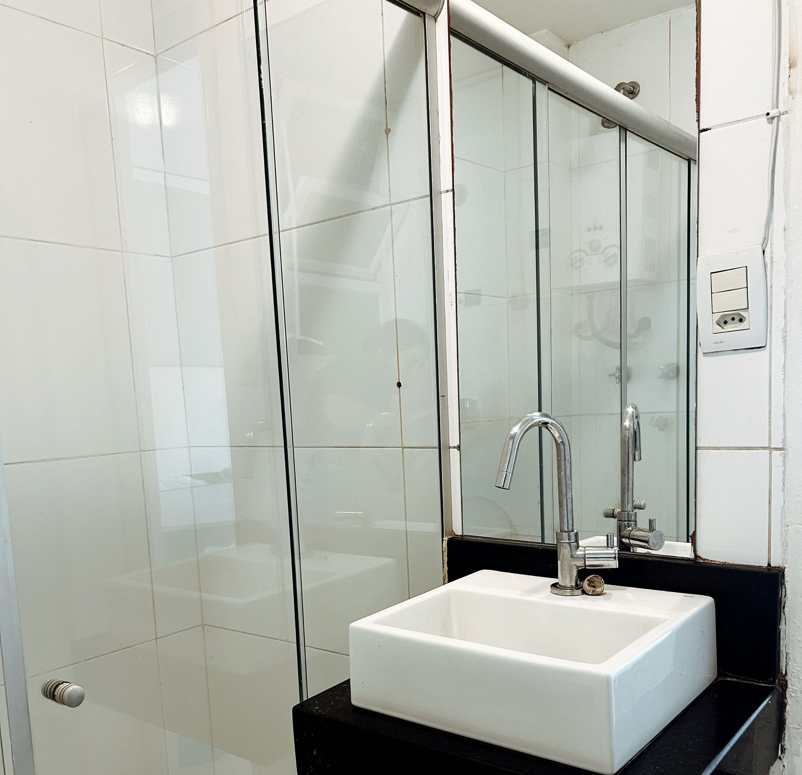 A bathroom with a white sink, a mirror, and a glass shower enclosure.