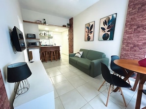 A modern living space with a kitchen, dining area, and a green sofa.