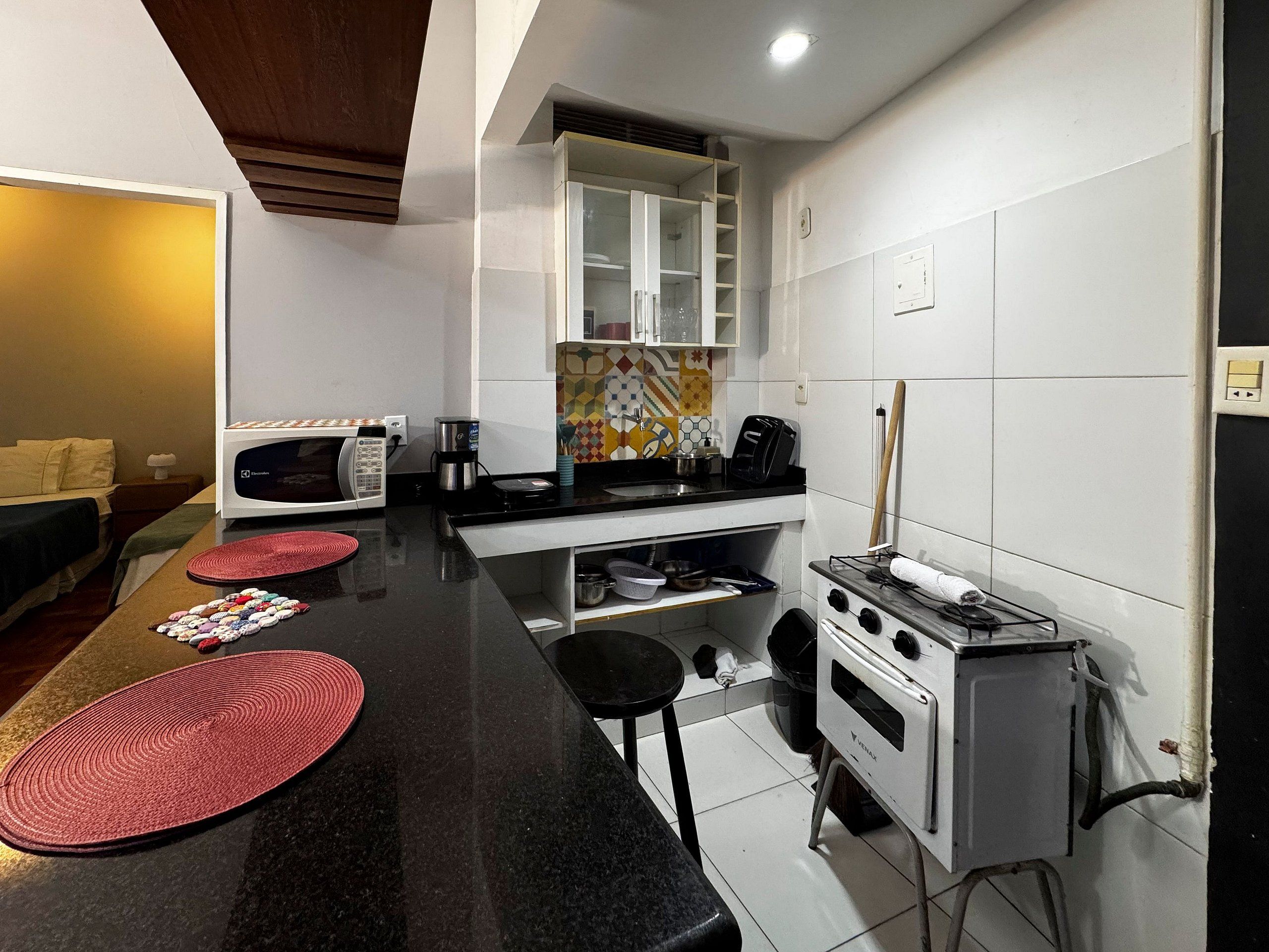 A compact kitchen with a microwave, coffee maker, toaster, and a small oven.