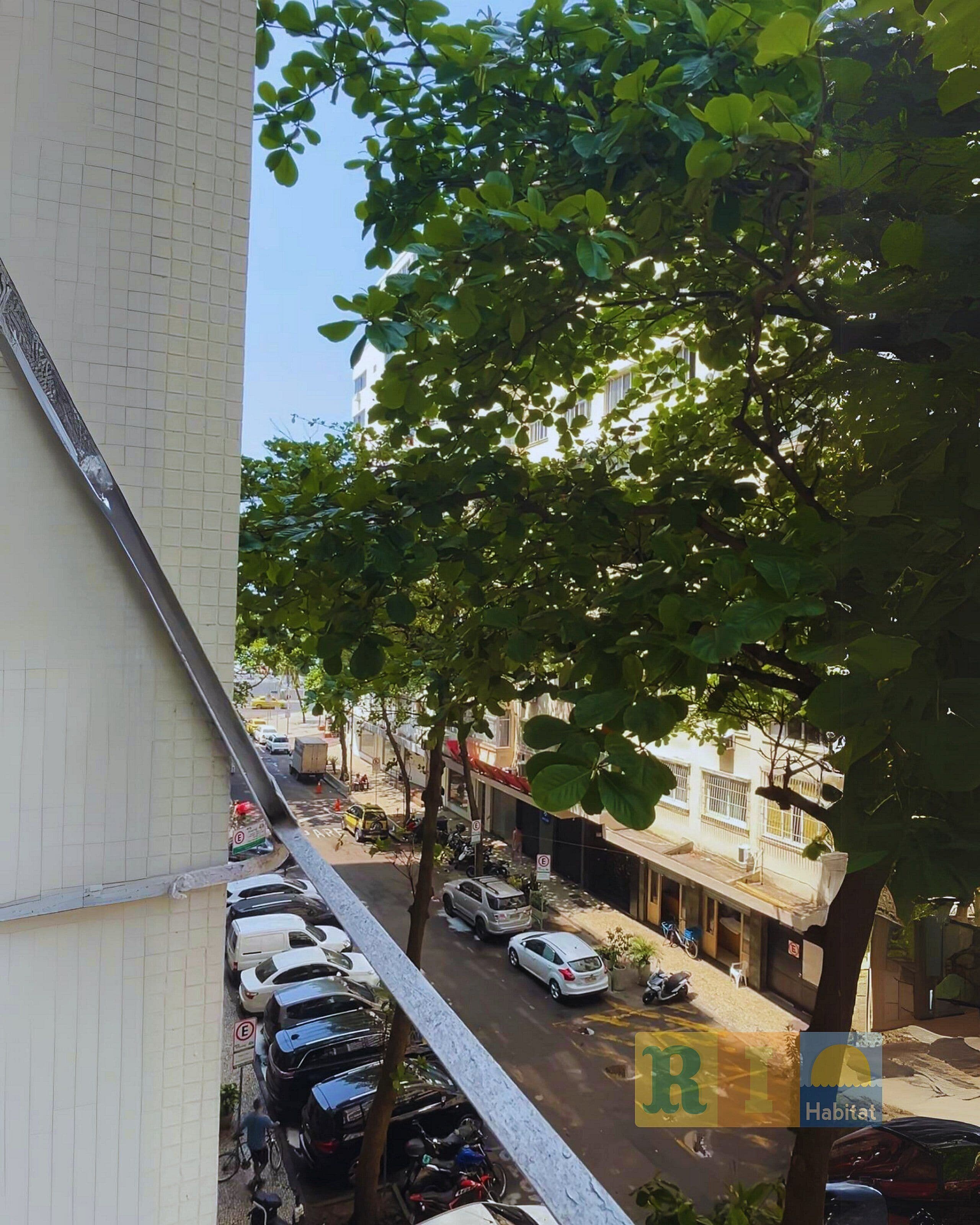 Una calle residencial con coches estacionados y un árbol que da sombra.