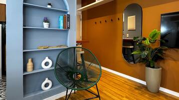 Un interior moderno con piso de madera, una silla verde, una estantería y una planta en maceta.