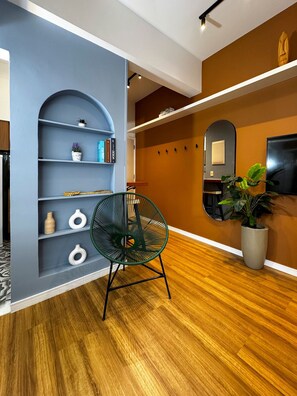 A modern interior with a wooden floor, a green chair, a bookshelf, and a potted plant. - Rio Habitat Almirante (Rio de Janeiro)