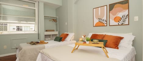 Un dormitorio con dos camas, una ventana con persianas, una mesita de noche con lámpara y una obra de arte en la pared.