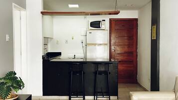 Una cocina moderna con refrigerador, microondas y taburetes de bar.