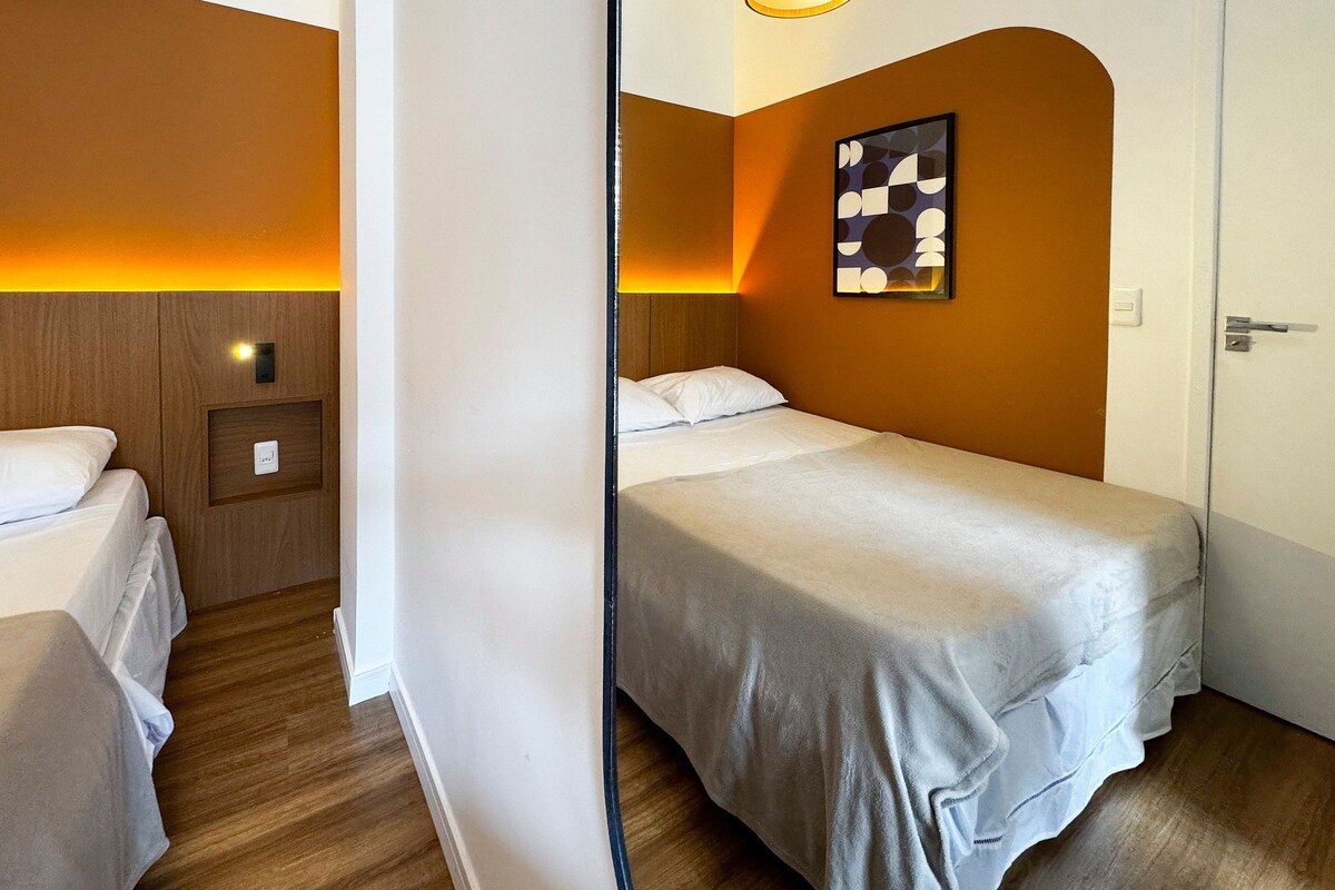 Une chambre d’hôtel comprenant un lit, une table de chevet, une lampe et une œuvre d’art accrochée au mur.