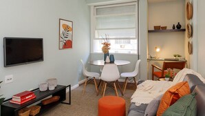 A living room with a flat-screen TV, a dining table with chairs, a sofa with cushions, a ceiling fan, and a window with blinds. - Rio Habitat Almirante (Rio de Janeiro)