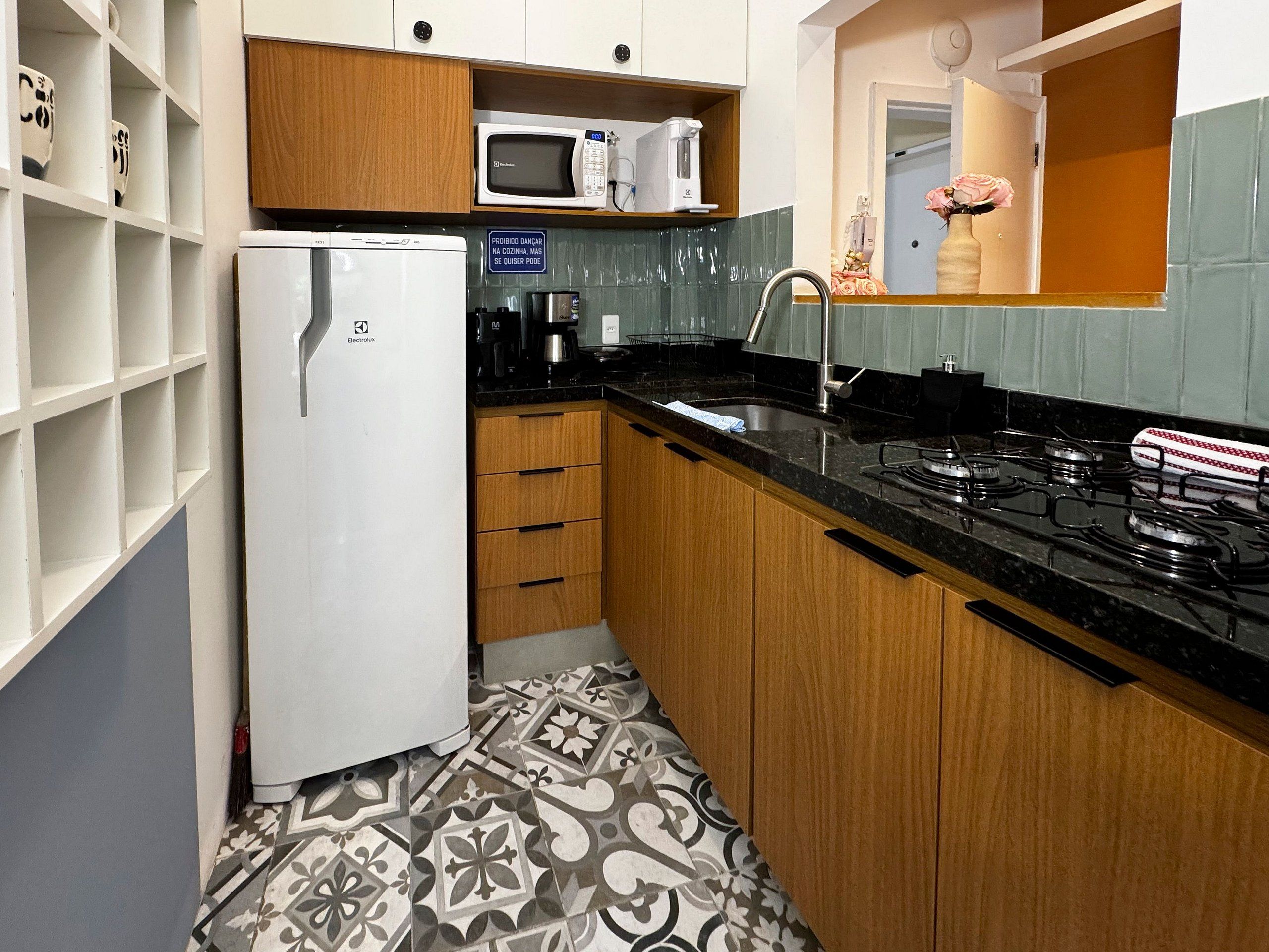 A compact kitchen with a refrigerator, microwave, sink, and stove.
