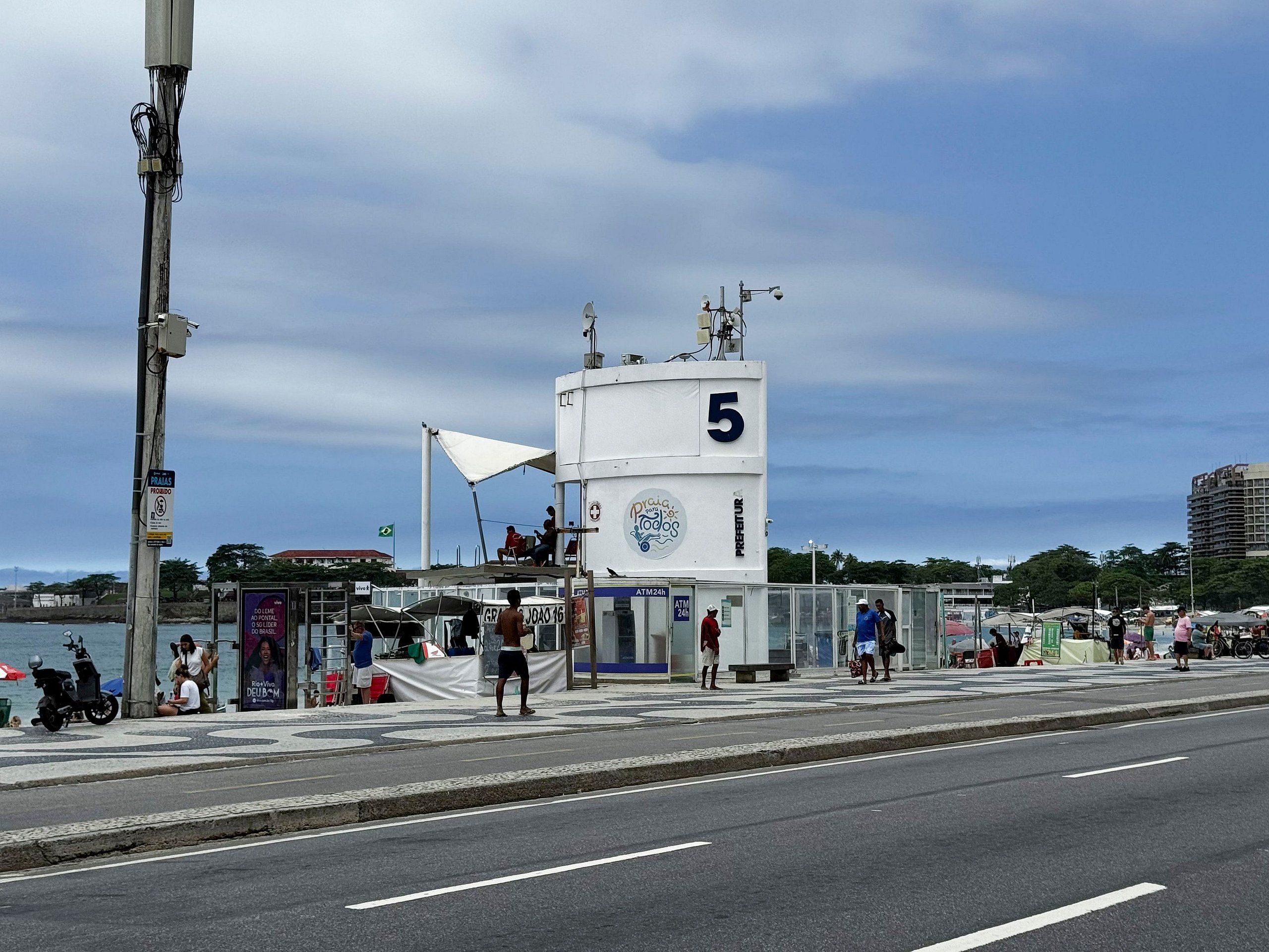 Kystlandskab med en markant hvid bygning med nummer 5, en kiosk og en klar himmel.