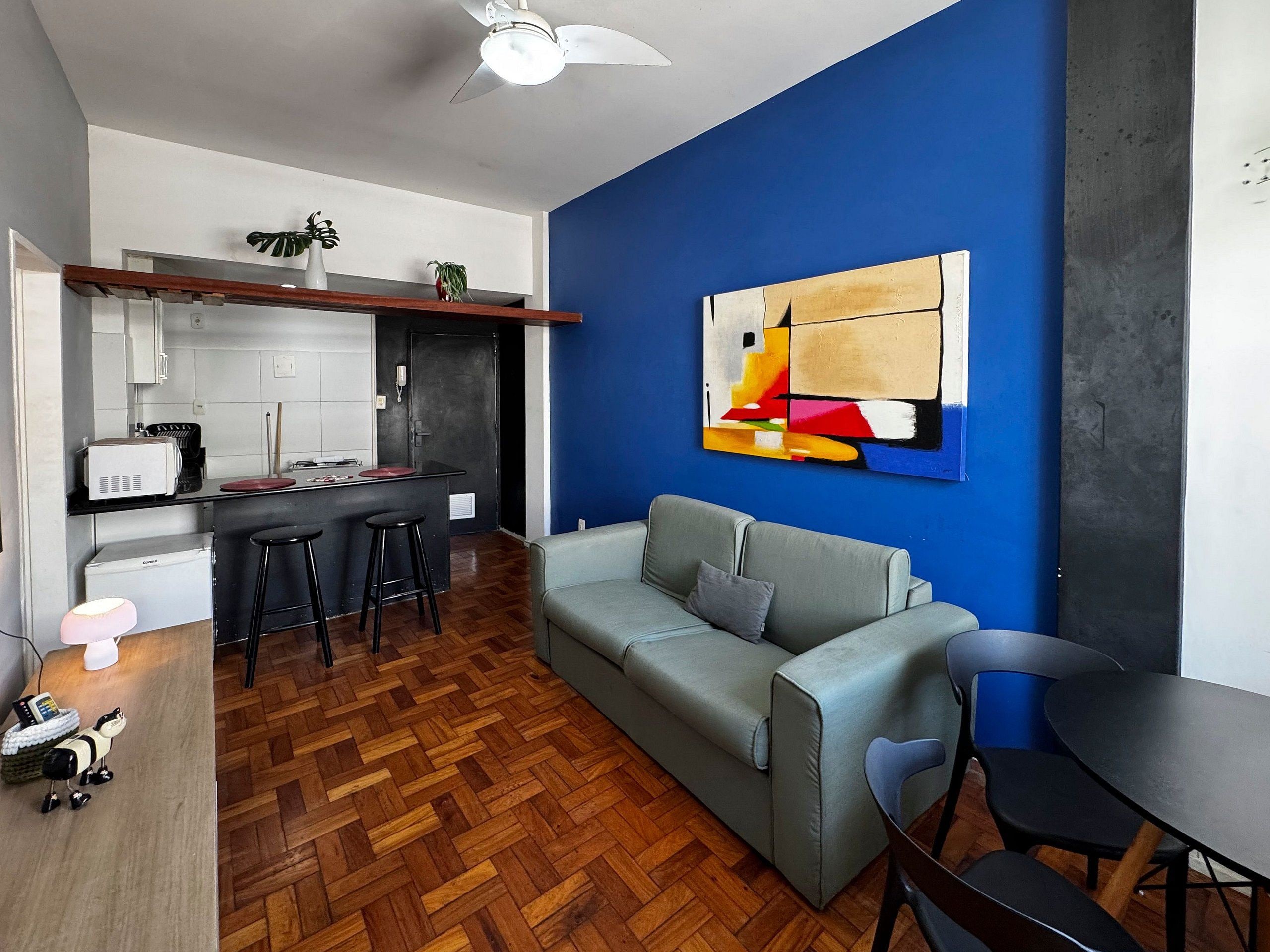 A modern living space with a kitchenette, a grey sofa, and a dining area.