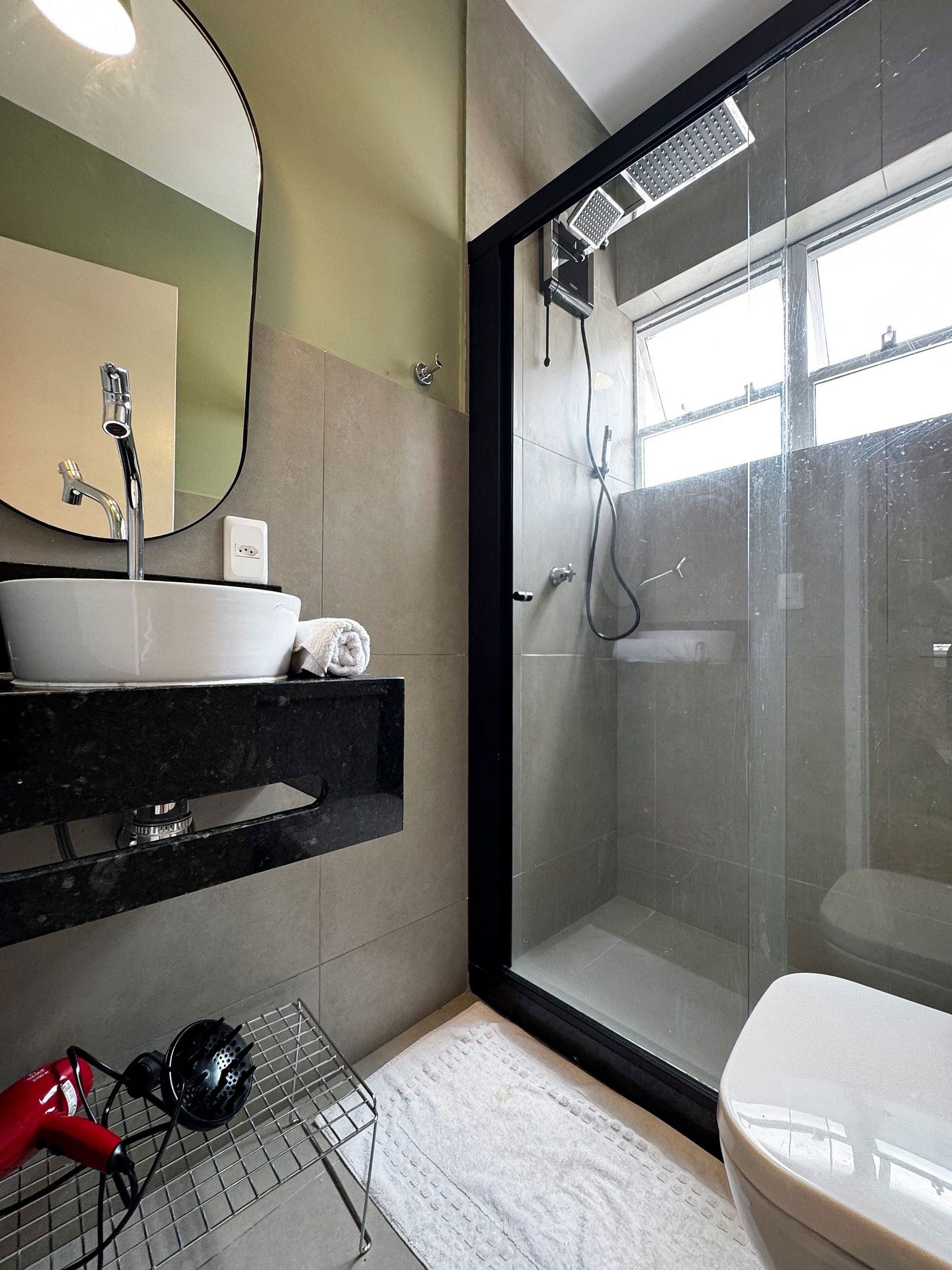 A modern bathroom with a glass-enclosed shower, a white sink, and a black countertop.