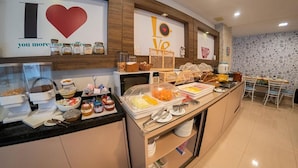 Zona de desayuno tipo buffet con diversas opciones de comida y una estación de café.