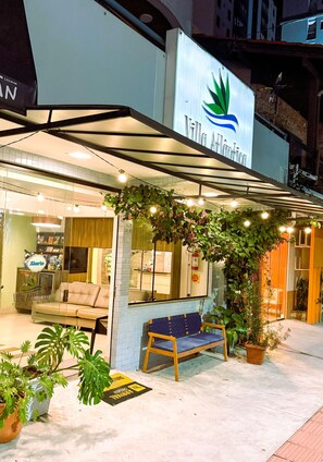 A hotel entrance with a sign, a seating area, and potted plants. - Pousada Villa Atlântica (Balneário Camboriú)