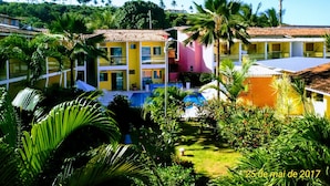 Ein Resort mit mehreren farbenfrohen Gebäuden, einem Schwimmbad und üppiger tropischer Vegetation.