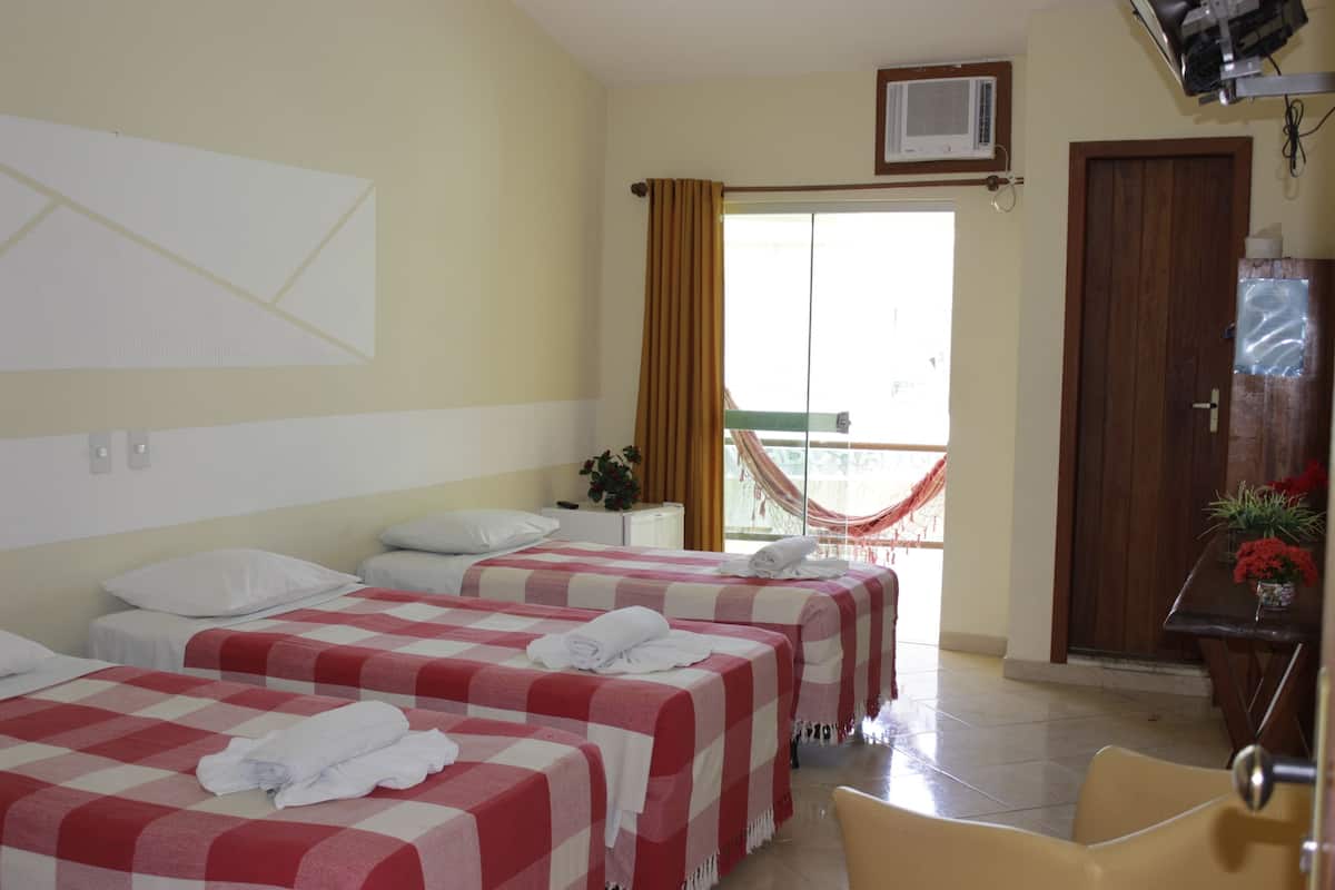 Quarto de hotel com duas camas, uma varanda e uma porta de madeira.