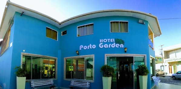 A blue building with the sign "Hotel Porto Garden" and large windows.