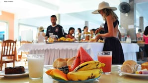 Ein Essbereich mit einem Tisch, der für eine Mahlzeit gedeckt ist, einschließlich einer Fruchtschale, einem Glas Milch und einem Glas Saft.