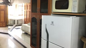 A kitchen with wooden cabinets, a white refrigerator, and a microwave on top. - Rio Habitat Posto 3 Copacabana (Rio de Janeiro)