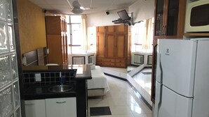 A compact kitchen with a refrigerator, a sink, and wooden cabinets. - Rio Habitat Posto 3 Copacabana (Rio de Janeiro)