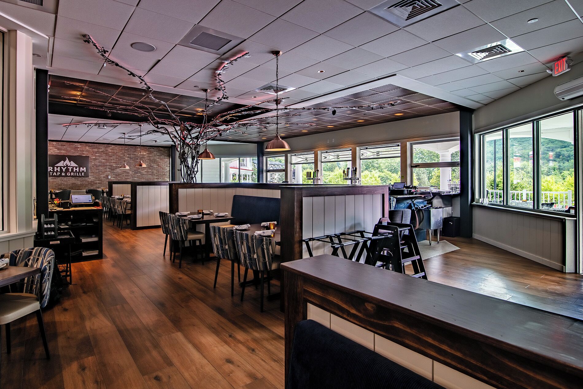 A restaurant with wooden flooring, tables, chairs, and a bar area.