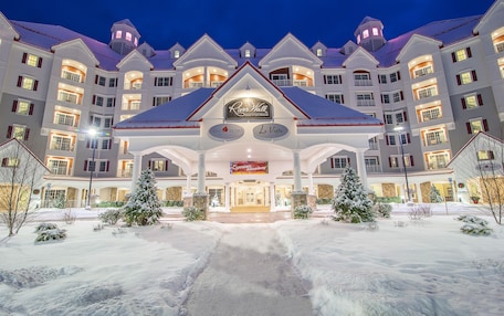 A large hotel with a central entrance, multiple balconies, and snow-covered surroundings.