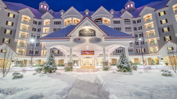 Un gran hotel con entrada central, varios balcones y alrededores cubiertos de nieve.