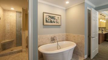 A bathroom with a freestanding bathtub, a shower enclosure, and a framed picture on the wall.