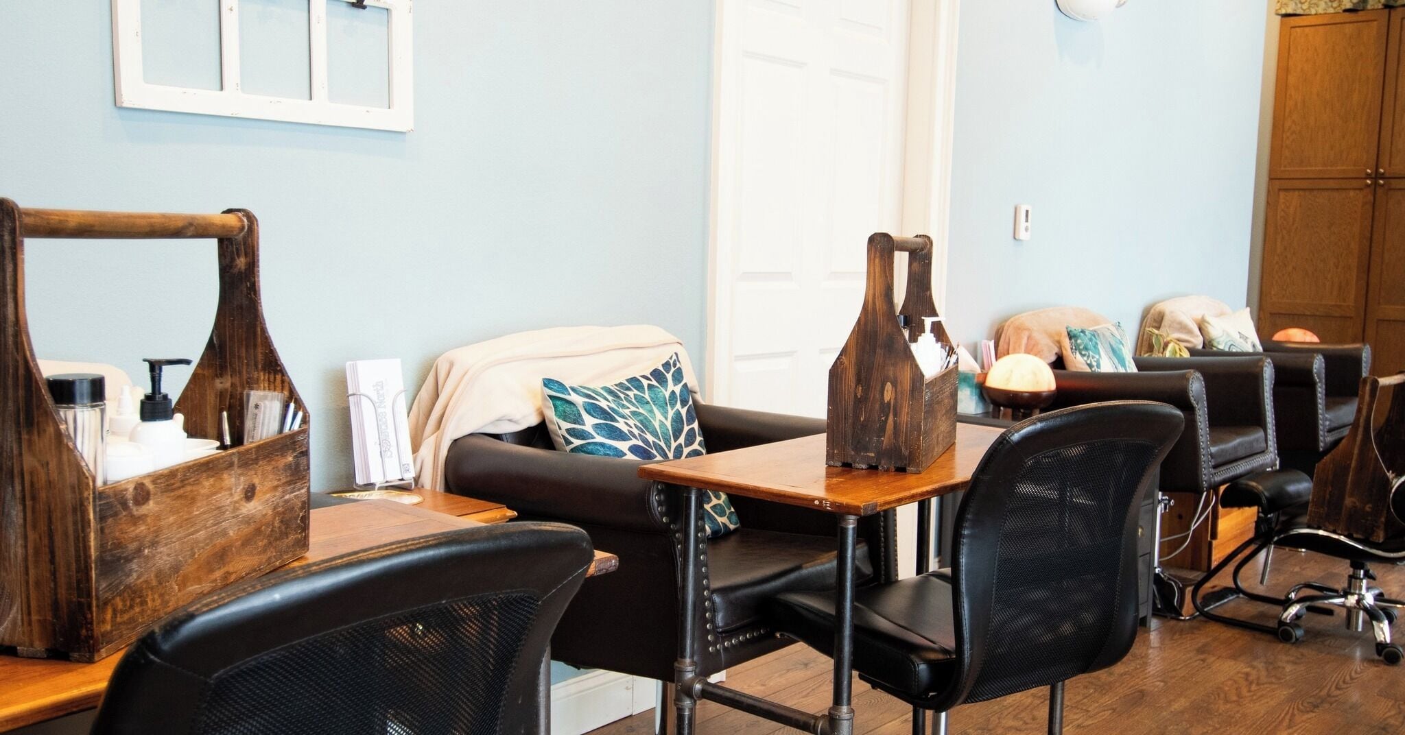 Un salon avec une coiffeuse en bois, des fauteuils en cuir noir et un mur bleu.