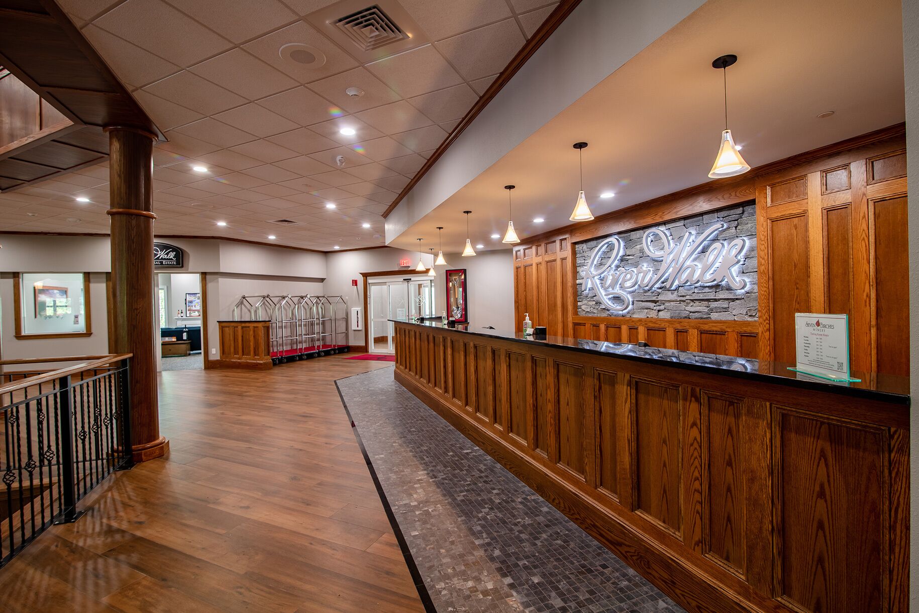 A reception area with a wooden reception desk, a stone wall with a sign, and a tiled floor.