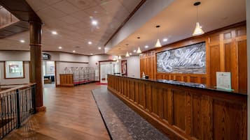 A reception area with a wooden reception desk, a stone wall with a sign, and a tiled floor.