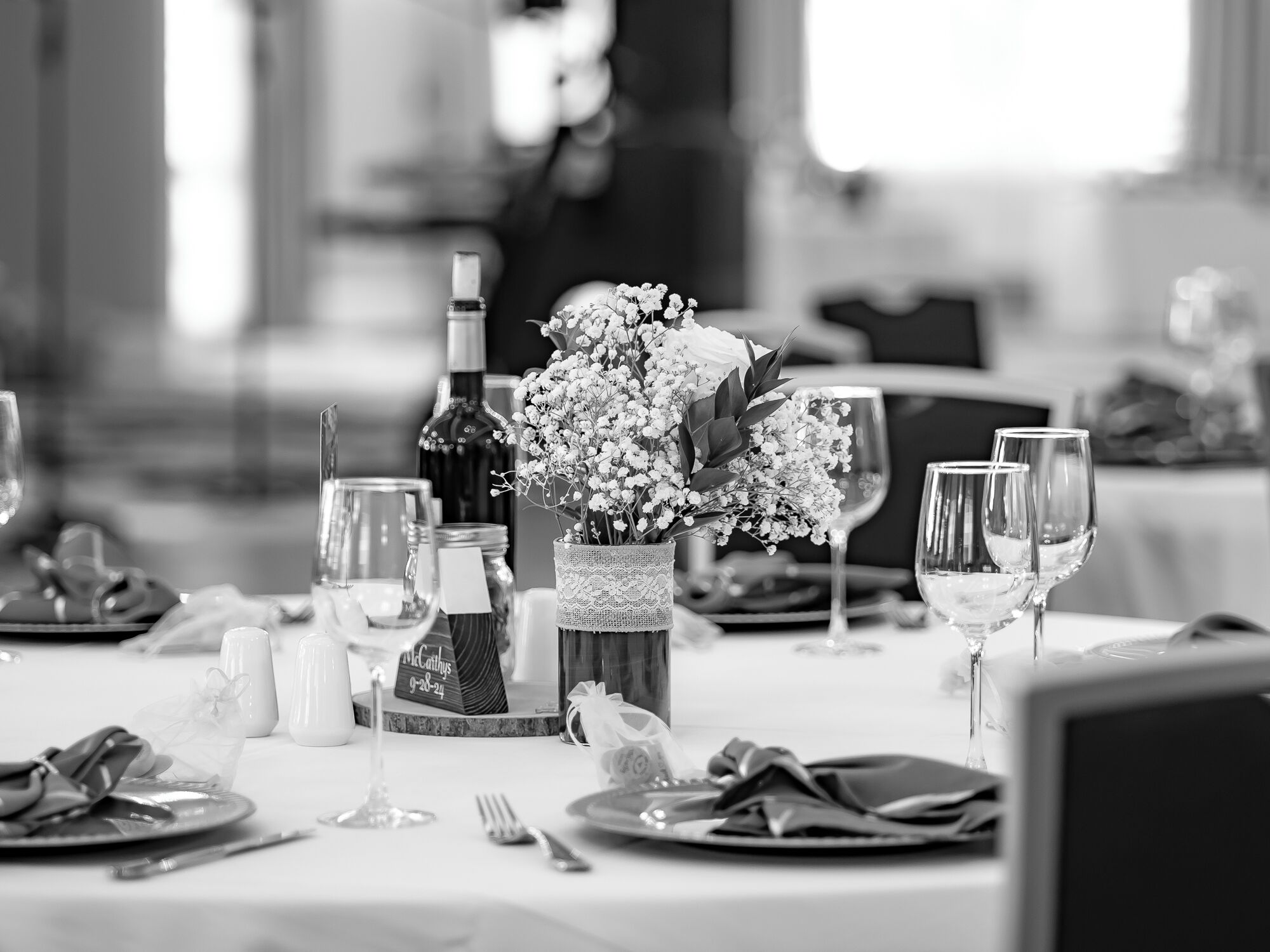 A dining table set with plates, cutlery, wine glasses, and a bottle of wine.