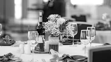 A dining table set with plates, cutlery, wine glasses, and a bottle of wine.