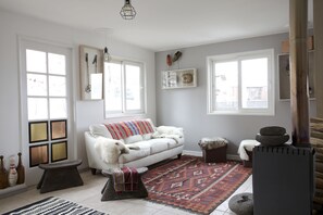 A cozy living room with a white sofa, a patterned rug, and a wood-burning stove. - Apart Bianco Hotel (Lo Barnechea)