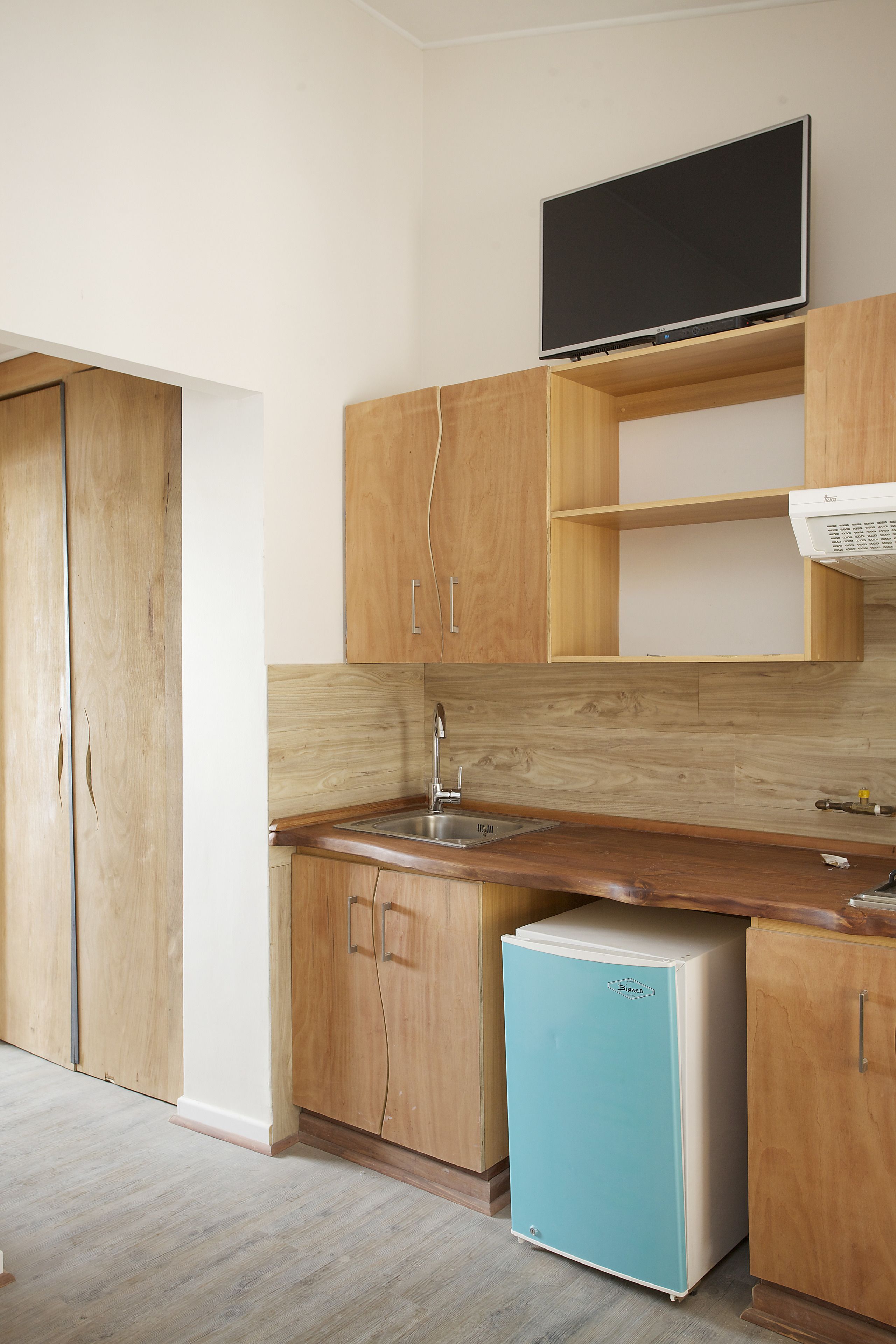 A compact kitchen with wooden cabinets, a built-in microwave, and a small refrigerator.