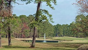 Golfkenttä, jossa on suihkulähde, puita ja hyvin hoidettu nurmikko.