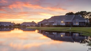 Una hilera de casas modernas con un lago tranquilo que refleja el atardecer.
