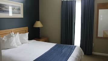 A hotel room with a bed, a nightstand, a lamp, and a window with curtains.