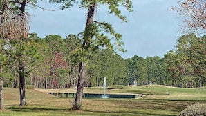A golf course with a fountain, trees, and a well-maintained lawn. - Windjammer Villas II (New Bern)