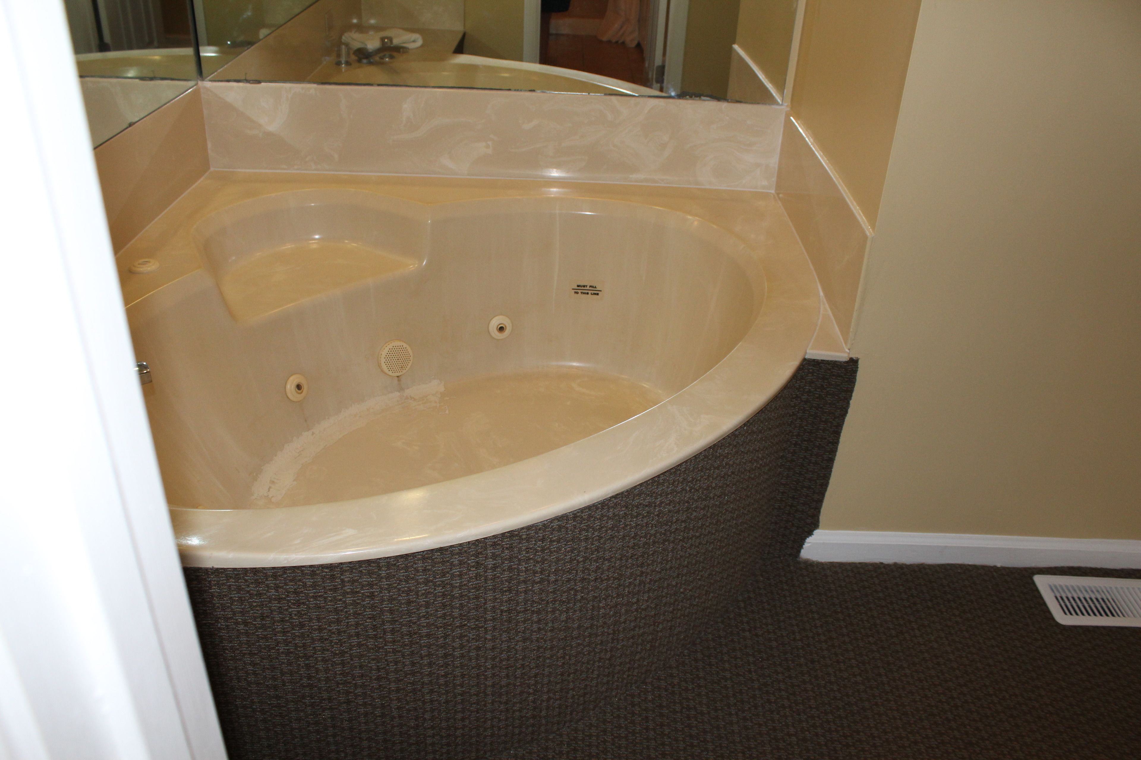 A bathroom with a large bathtub, a mirror, and a shower area.
