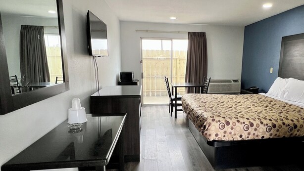 Une chambre d’hôtel avec un lit, un bureau, une chaise, une télévision et un balcon.