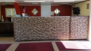 Un espace d’accueil agrémenté d’une cloison décorative, d’un bureau sur lequel sont disposés divers objets et d’un miroir mural.